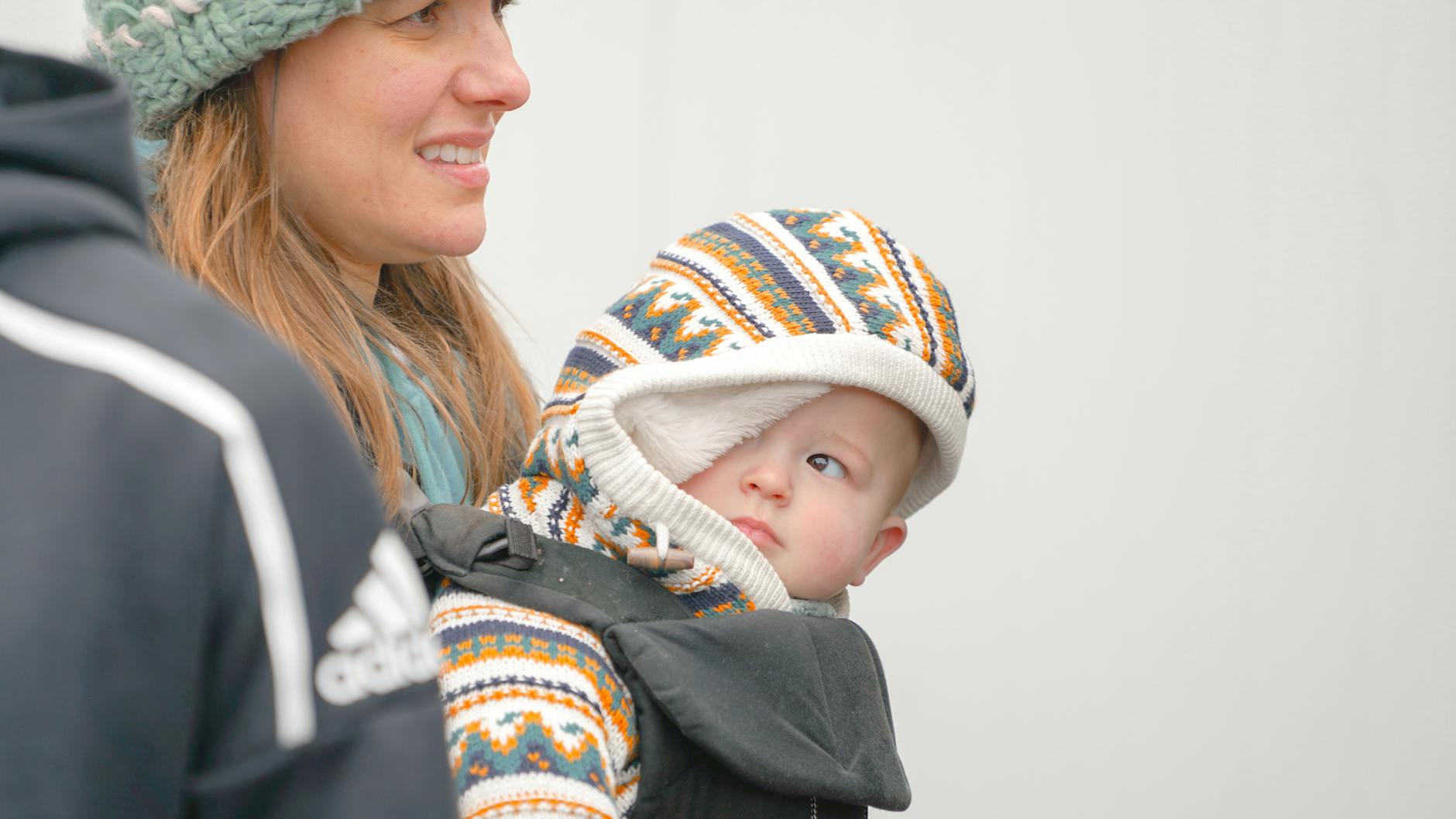 Mama nosi dziecko w chuście zimą podczas spaceru na świeżym powietrzu