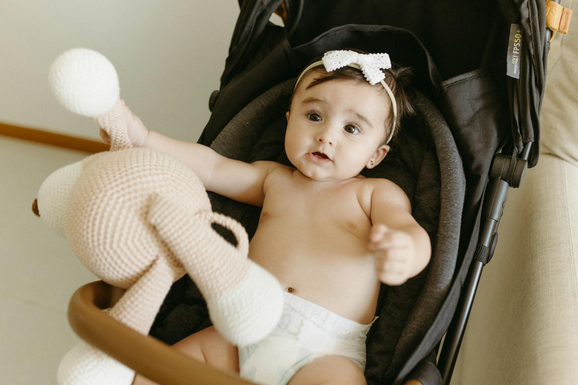 Niemowlę w spacerówce trzymające szydełkową zabawkę