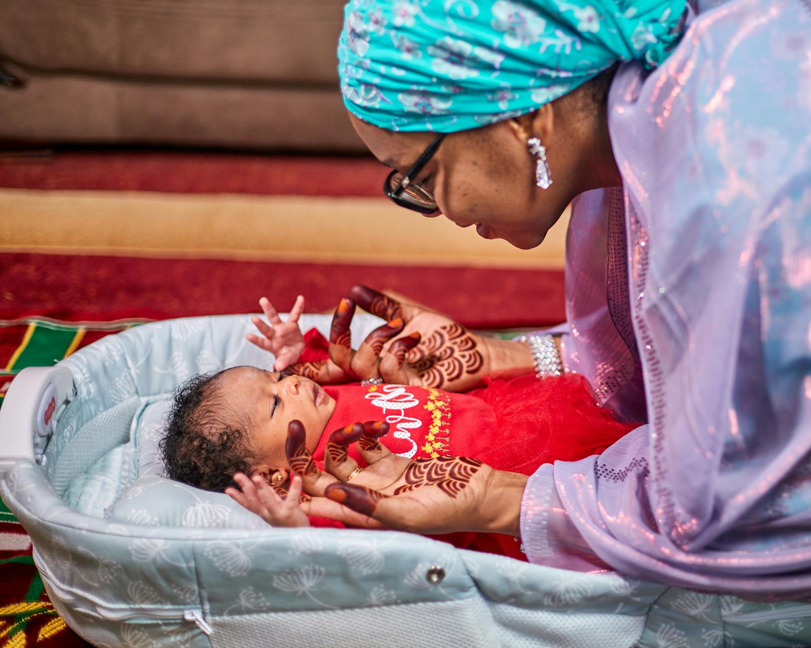 Mama z henną na dłoniach trzyma niemowlę w domu w Nigerii
