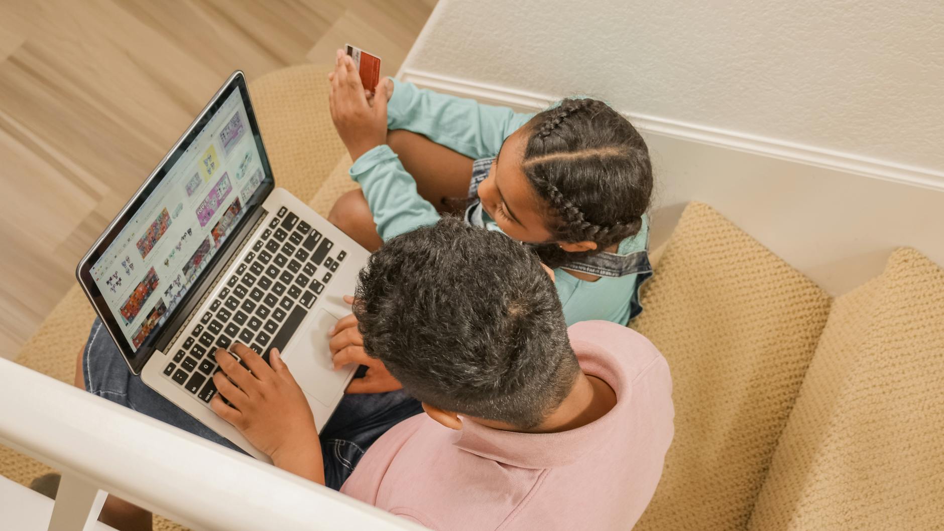 Tata z córką na schodach przeglądają dziecięcy sklep online na laptopie