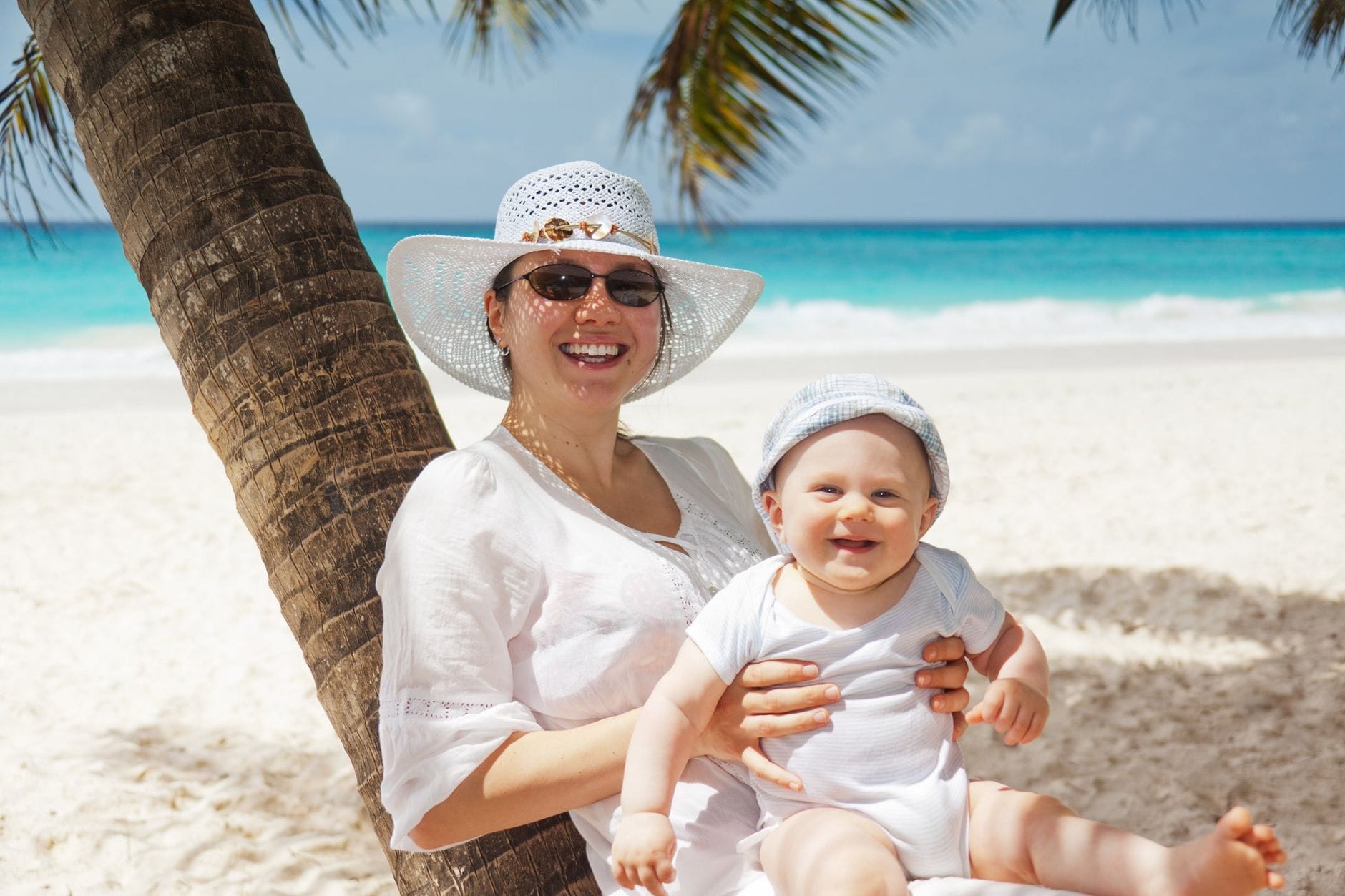 Wakacje z rocznym dzieckiem nad morzem – lista rzeczy naprawdę potrzebnych Mama z rocznym dzieckiem odpoczywa na plaży pod palmami